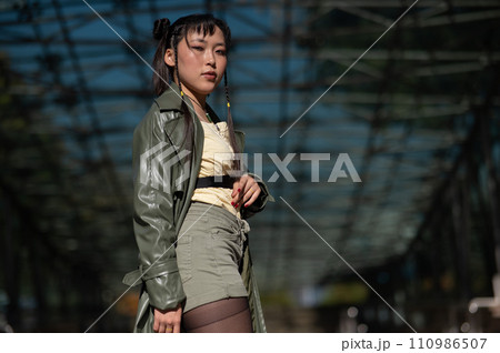 A beautiful Asian woman in shorts and a green leather coat comes out of the subway. A beautiful Asian woman in shorts and a green leather coat comes out of the subway. 110986507