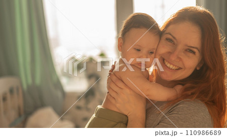 A Caucasian woman tenderly holds her newborn son in the morning rays of sunlight. 110986689