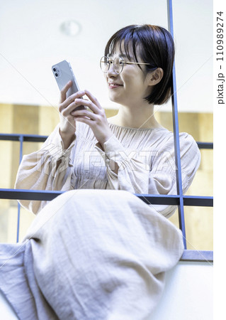 室内ブリッジに座ってスマホを使う女性 室内ブリッジに座ってスマホを使う女性 110989274