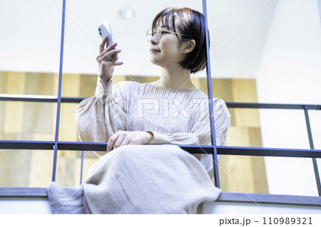 室内ブリッジに座ってスマホを使う女性 室内ブリッジに座ってスマホを使う女性 110989321