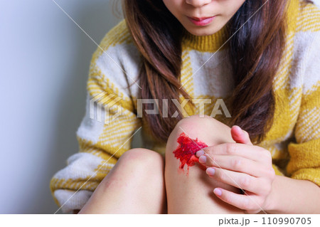 膝を擦りむいて床に座る女性（顔なし） 110990705