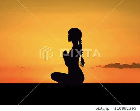 夕焼けの前でヨガの「合掌ポーズ」をする女性シルエット横から 110992395