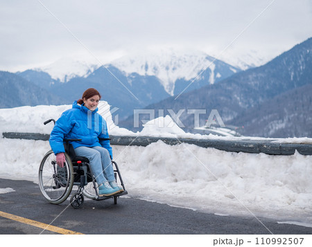 Caucasian woman in a wheelchair travels in the mountains in winter. 110992507