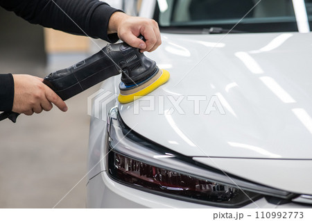 Process of polishing white car hood surface using orbital polishing machine.  110992773