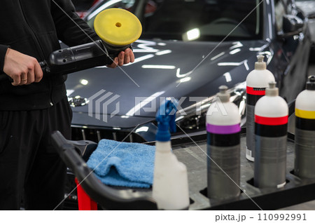 The master applies a special composition to the device for polishing the surface of the car body. The master applies a special composition to the device for polishing the surface of the car body. 110992991