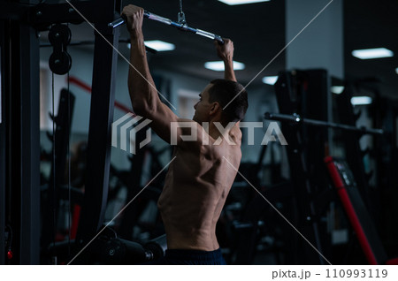 A man does a chest pulldown in the gym. A man does a chest pulldown in the gym. 110993119