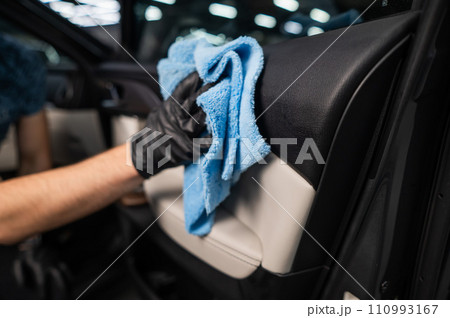 A man wipes the surface of the car interior with a microfiber cloth. A man wipes the surface of the car interior with a microfiber cloth. 110993167