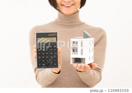 家と電卓を持って微笑むミドル女性 110993350