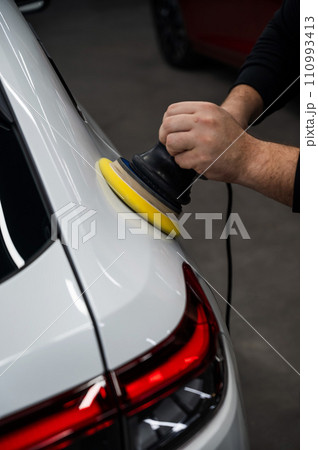 Process of polishing white car body surface using orbital polishing machine. Vertical photo. Process of polishing white car body surface using orbital polishing machine. Vertical photo. 110993413