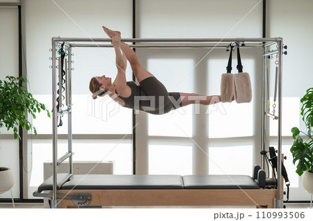 A pregnant woman is doing Pilates on a reformer. Aerial gymnastics. A pregnant woman is doing Pilates on a reformer. Aerial gymnastics. 110993506