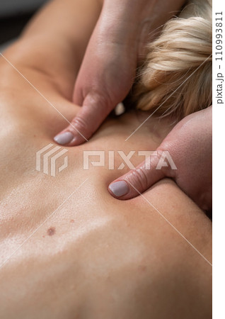 A woman undergoing a massage of the cervical-collar area. 110993811