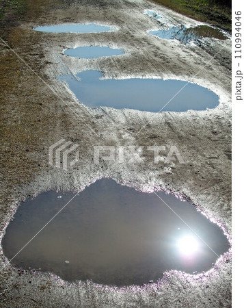 秋の雨上がりの江戸川河川敷の水溜まりのある砂利道風景 秋の雨上がりの江戸川河川敷の水溜まりのある砂利道風景 110994046