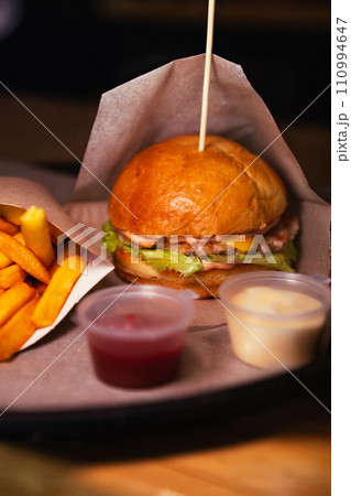 Side view of cheeseburger with chicken and fries with sauce. High quality photo. Selective focus. Unhealthy eating concept 110994647
