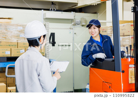 倉庫でフォークリフトを操作する女性作業員 110995822