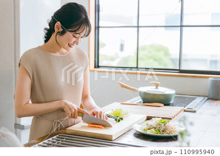 キッチンで料理・家事をする若い女性・妻・主婦（包丁・切る・野菜） 110995940