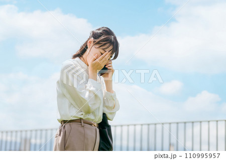 トラブル・悲報・訃報の連絡を受けて顔を覆うビジネスウーマン・ワーキングウーマン トラブル・悲報・訃報の連絡を受けて顔を覆うビジネスウーマン・ワーキングウーマン 110995957