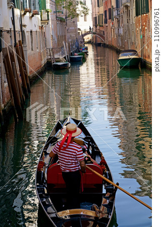A gondolier steals tourists on a boat. Venice, Veneto region, Italy - September 2023 110996761