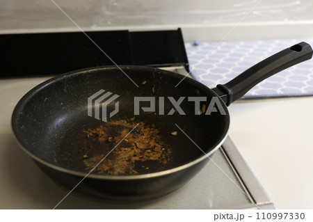 頑固な黒焦げの付着したフライパン 110997330