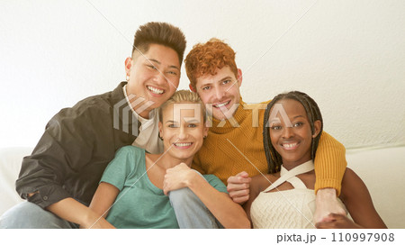 Multiethnic friends looking at camera laughing on the sofa Multiethnic friends looking at camera laughing on the sofa 110997908