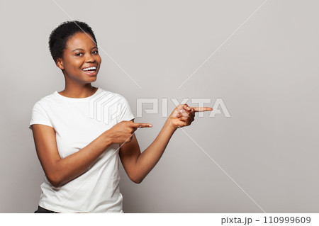 Attractive woman pointing finger at light gray studio wall banner background 110999609
