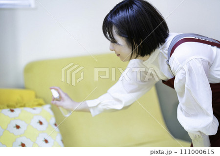 ソファを消毒するエプロンの女性 111000615