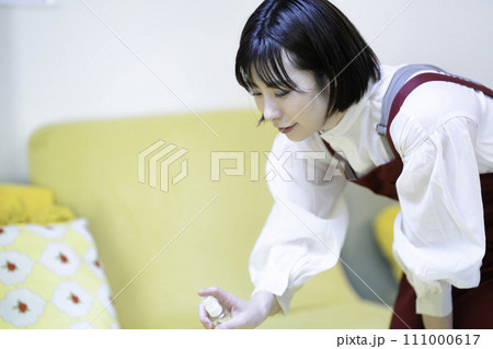 ソファを消毒するエプロンの女性 111000617
