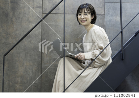 階段でノートパソコンを使う眼鏡の女性 階段でノートパソコンを使う眼鏡の女性 111002941