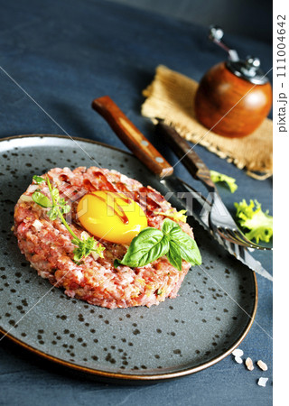 Top view of raw minced meat with liquid egg yolk for preparation of meatball placed on gray plate Top view of raw minced meat with liquid egg yolk for preparation of meatball placed on gray plate 111004642