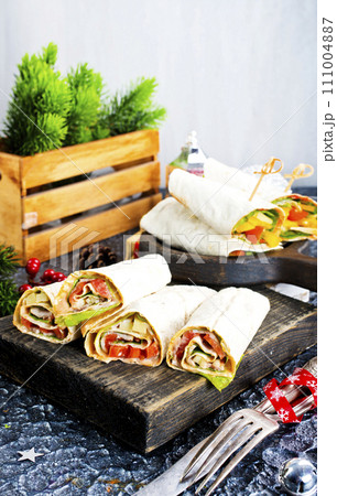 Salmon and cream cheese wraps. Rolls with smoked salmon, basil and rocket salad. Burrito on serving board 111004887