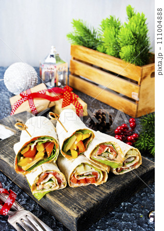 Salmon and cream cheese wraps. Rolls with smoked salmon, basil and rocket salad. Burrito on serving board 111004888