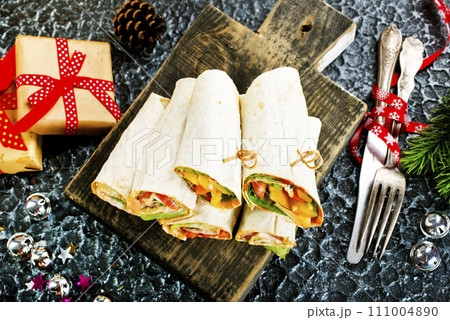 Salmon and cream cheese wraps. Rolls with smoked salmon, basil and rocket salad. Burrito on serving board 111004890