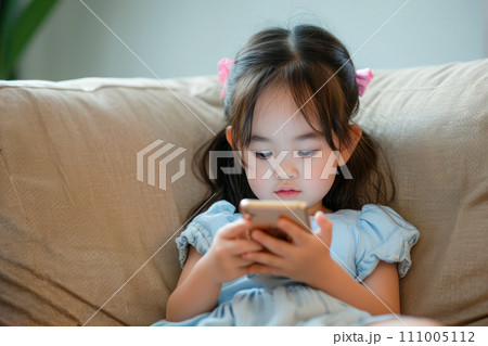 AI-generated content. Asian child sitting on a sofa, browsing internet on mobile device and playing with smartphone apps 111005112