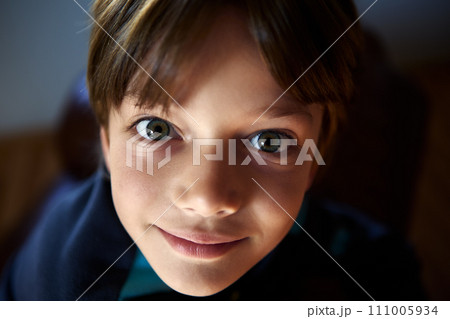 Young boy stare wide-eyed in shade room close up. 111005934