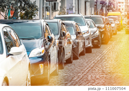 Many Cars parked in row on street in city in sunny summer day. ecological problem - air pollution Many Cars parked in row on street in city in sunny summer day. ecological problem - air pollution 111007504