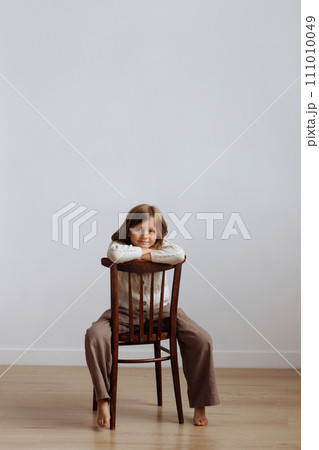 A child in casual clothes jumping on a bed with a pillow in his hands 111010049