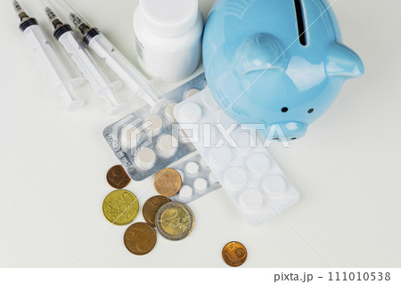 The blue piggy bank is surrounded by various medicines and euro coins 111010538