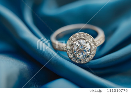 Diamond engagement ring on a blue silk background. Luxury female jewelry close up Diamond engagement ring on a blue silk background. Luxury female jewelry close up 111010776