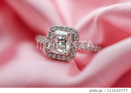 Diamond engagement ring on a pink silk background. Luxury female jewelry close-up 111010777