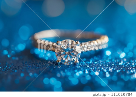 Diamond engagement ring on a blue shiny background. Luxury female jewelry close up 111010784