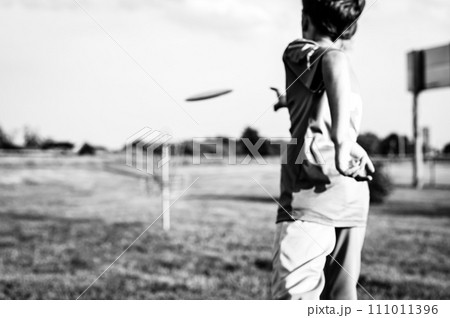 Selective focus fairway grass with a defocused young child holding a putter disc and golf goal in the distance.  Selective focus fairway grass with a defocused young child holding a putter disc and golf goal in the distance.  111011396
