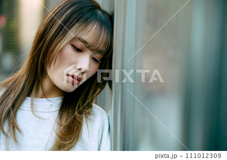 壁に寄りかかる若い女性 壁に寄りかかる若い女性 111012309