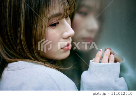 壁に寄りかかる若い女性 111012310