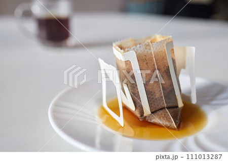 brewing process,a bag filled with boiling water for drip coffee in a cup,top view. brewing process,a bag filled with boiling water for drip coffee in a cup,top view. 111013287