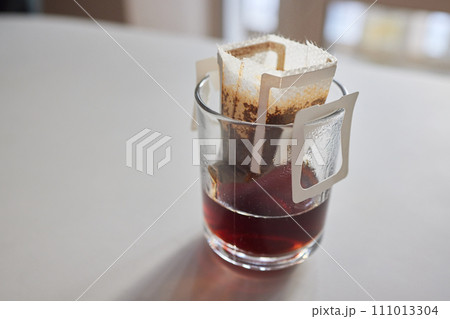 brewing process,a bag filled with boiling water for drip coffee in a cup,top view. brewing process,a bag filled with boiling water for drip coffee in a cup,top view. 111013304