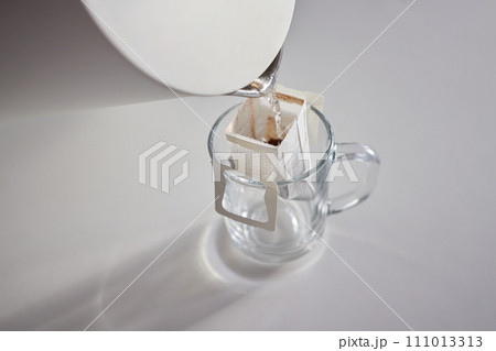 brewing process,a bag filled with boiling water for drip coffee in a cup,top view. brewing process,a bag filled with boiling water for drip coffee in a cup,top view. 111013313