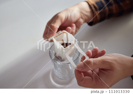 brewing process,a bag filled with boiling water for drip coffee in a cup,top view. brewing process,a bag filled with boiling water for drip coffee in a cup,top view. 111013330
