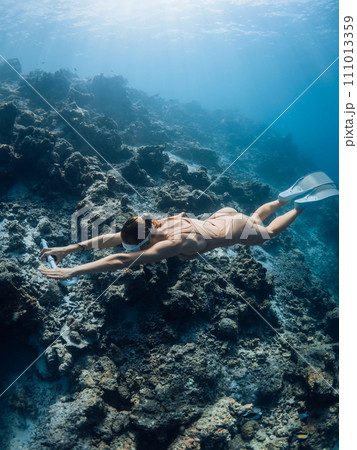 Woman freediver training on deep in ocean. Female freediver swims underwater 111013359
