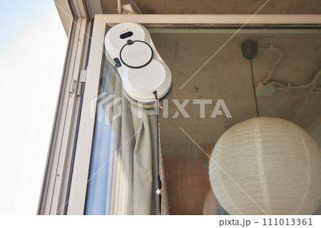 A window cleaner robot washes glass against the backdrop of multi-storey buildings. A window cleaner robot washes glass against the backdrop of multi-storey buildings. 111013361
