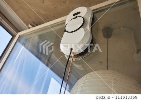 A window cleaner robot washes glass against the backdrop of multi-storey buildings. 111013369
