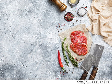 Fillet of raw beef rib eye steak on with meat cleaver,salt and pepper on light table 111013451